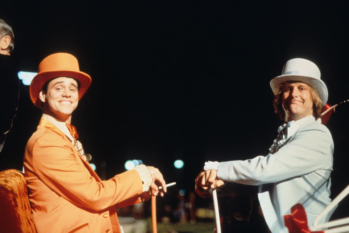 Jim Carrey and Jeff Daniels wear orange and blue suits, respectively, with matching top hats on the set of ‘Dumb & Dumber'