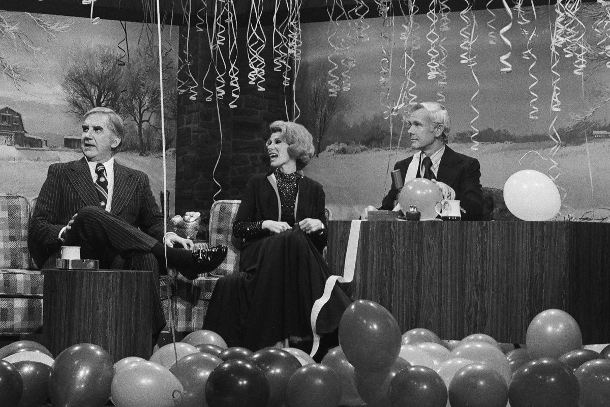 Ed McMahon, Joan Rivers, and Johnny Carson seated on 'The Tonight Show' panel decorated with streamers and balloons