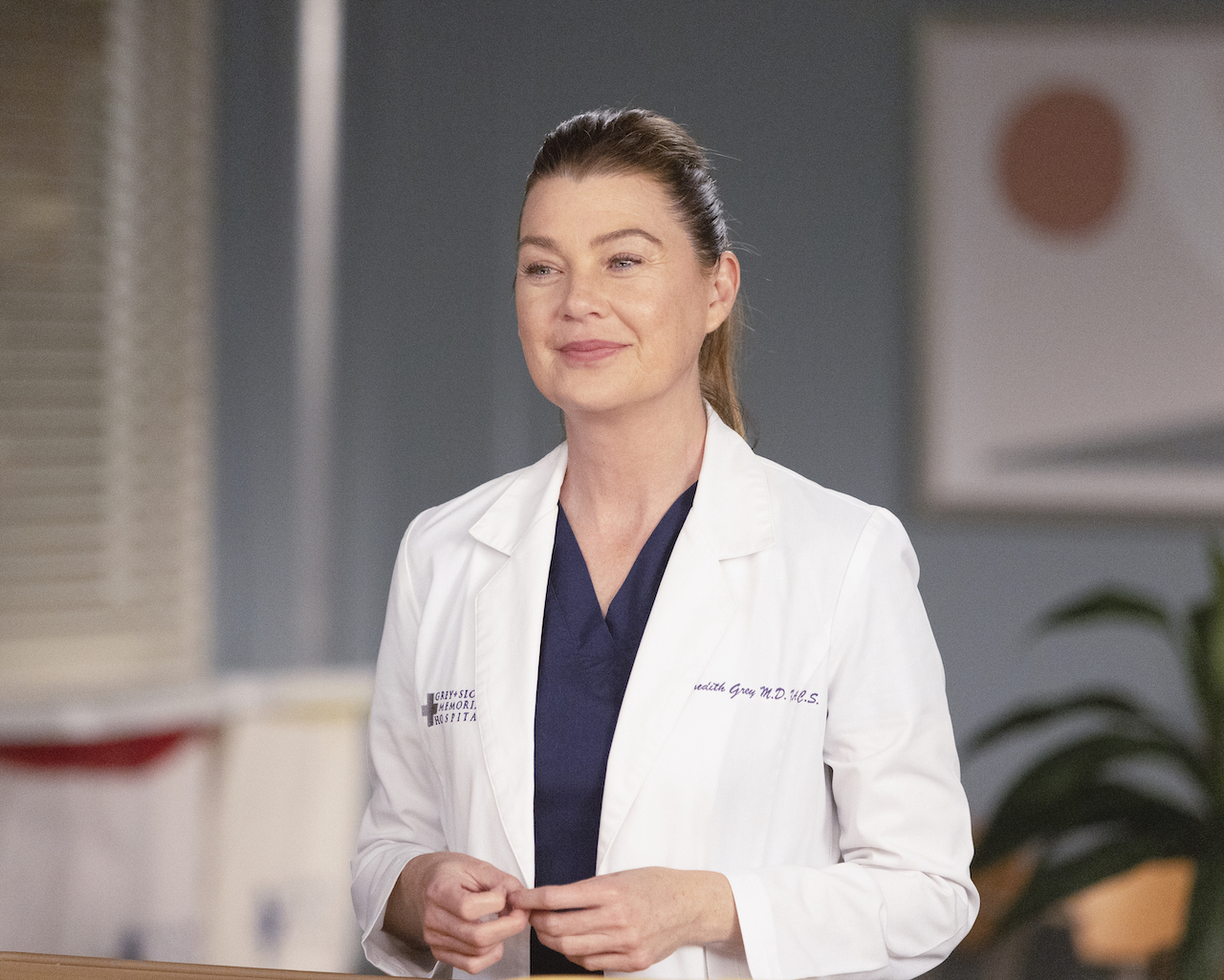 Ellen Pompeo as Meredith Grey wears her white doctor's coat over blue scrubs on 'Grey's Anatomy'