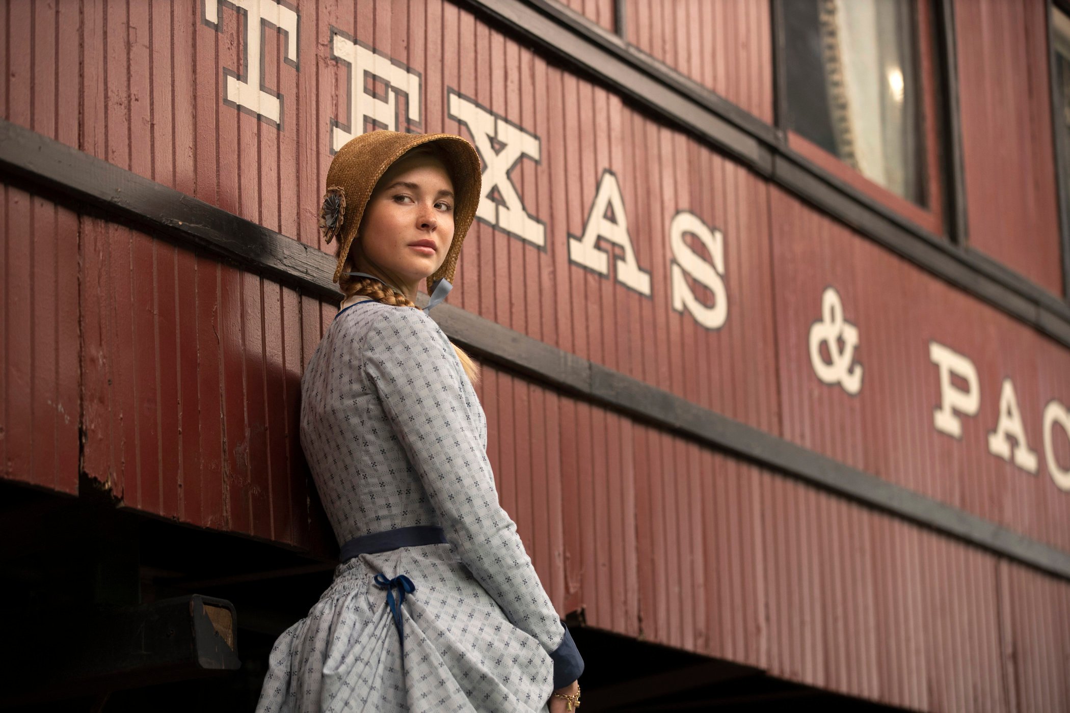 Isabel May as Elsa Dutton standing next to a train and looking over her shoulder in '1883'