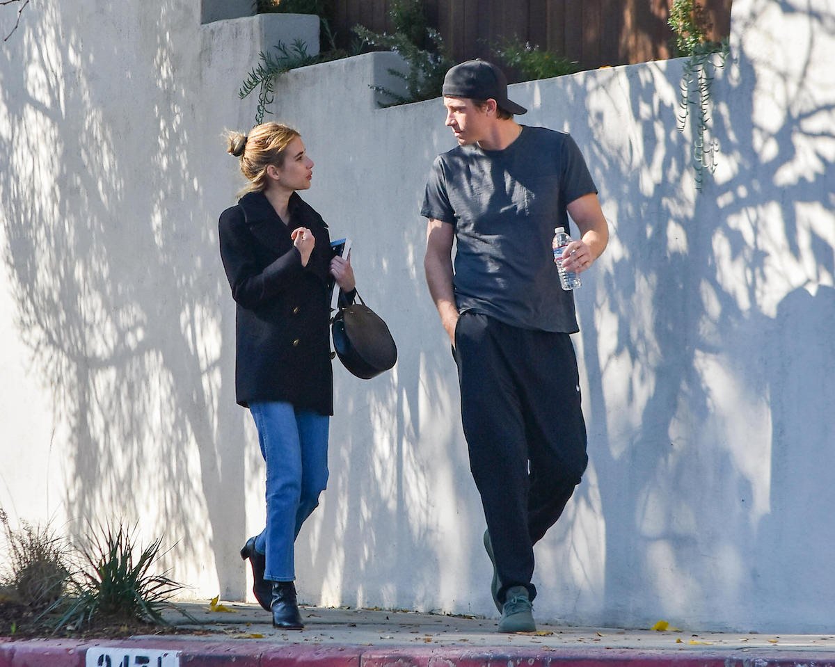 Emma Roberts and Garrett Hedlund walk on a sidewalk together in casual clothes.