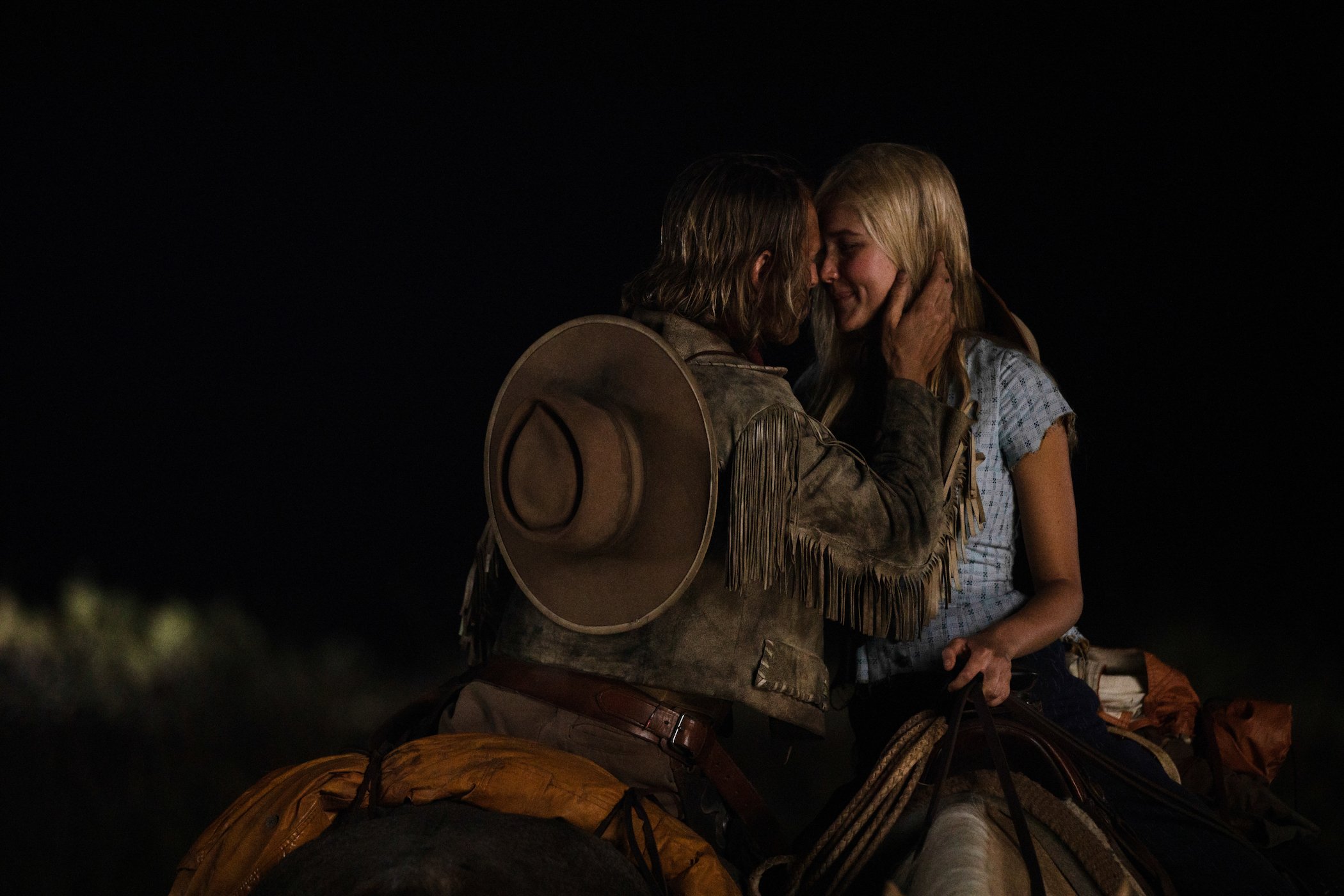 Eric Nelsen as Ennis and Isabel May as Elsa kissing in the dark while riding horses in '1883' 