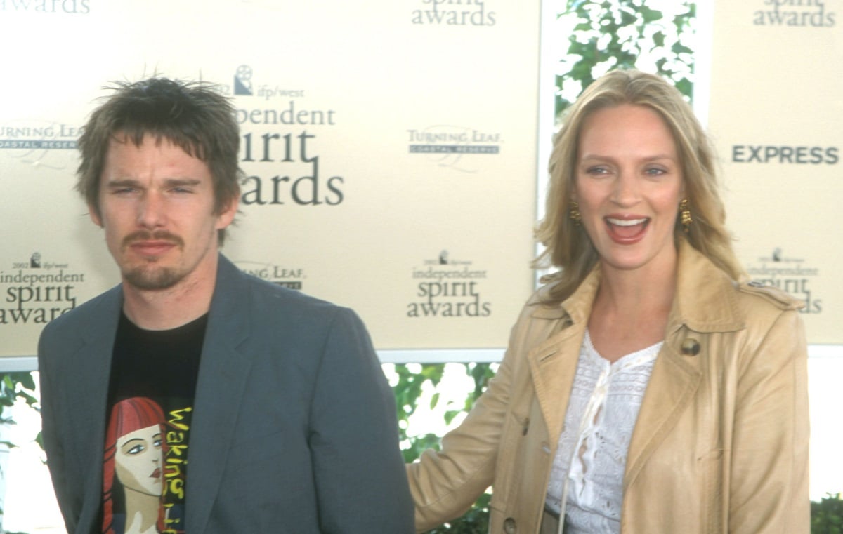 Uma Thurman smiling while holding Ethan Hawke's hand.