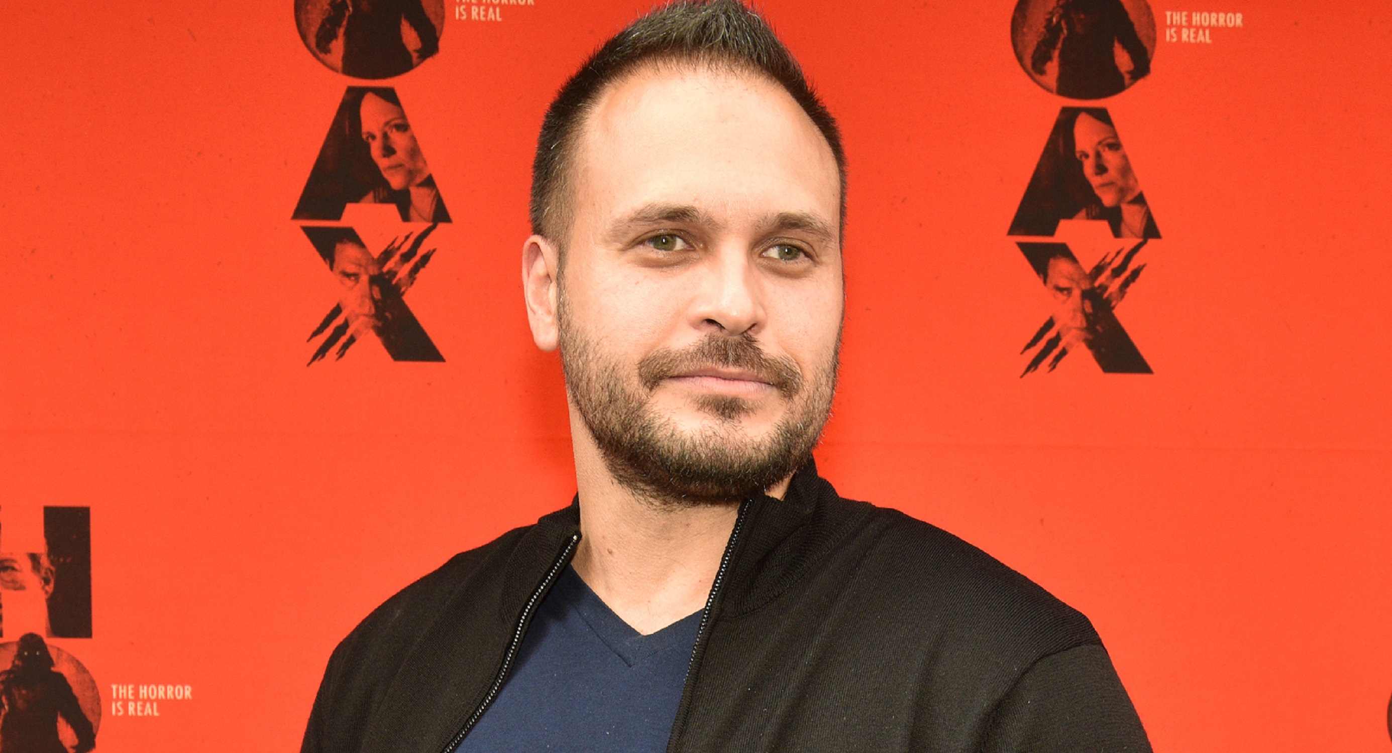 General Hospital comings and goings focus on Max Decker, pictured here in a blue shirt and black jacket against a red background