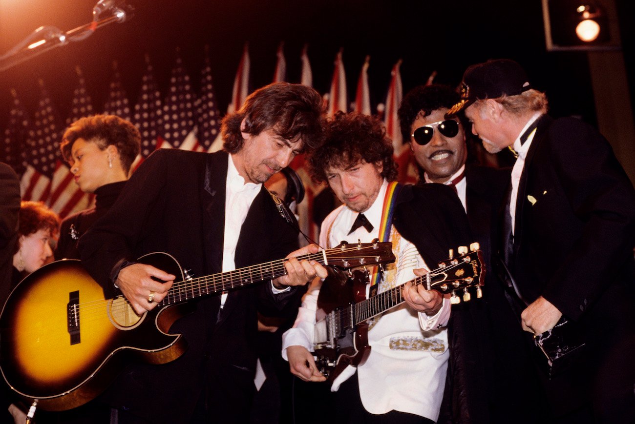 George Harrison and Bob Dylan wearing suits while performing at the 1988 Rock & Roll Hall of Fame induction ceremony.