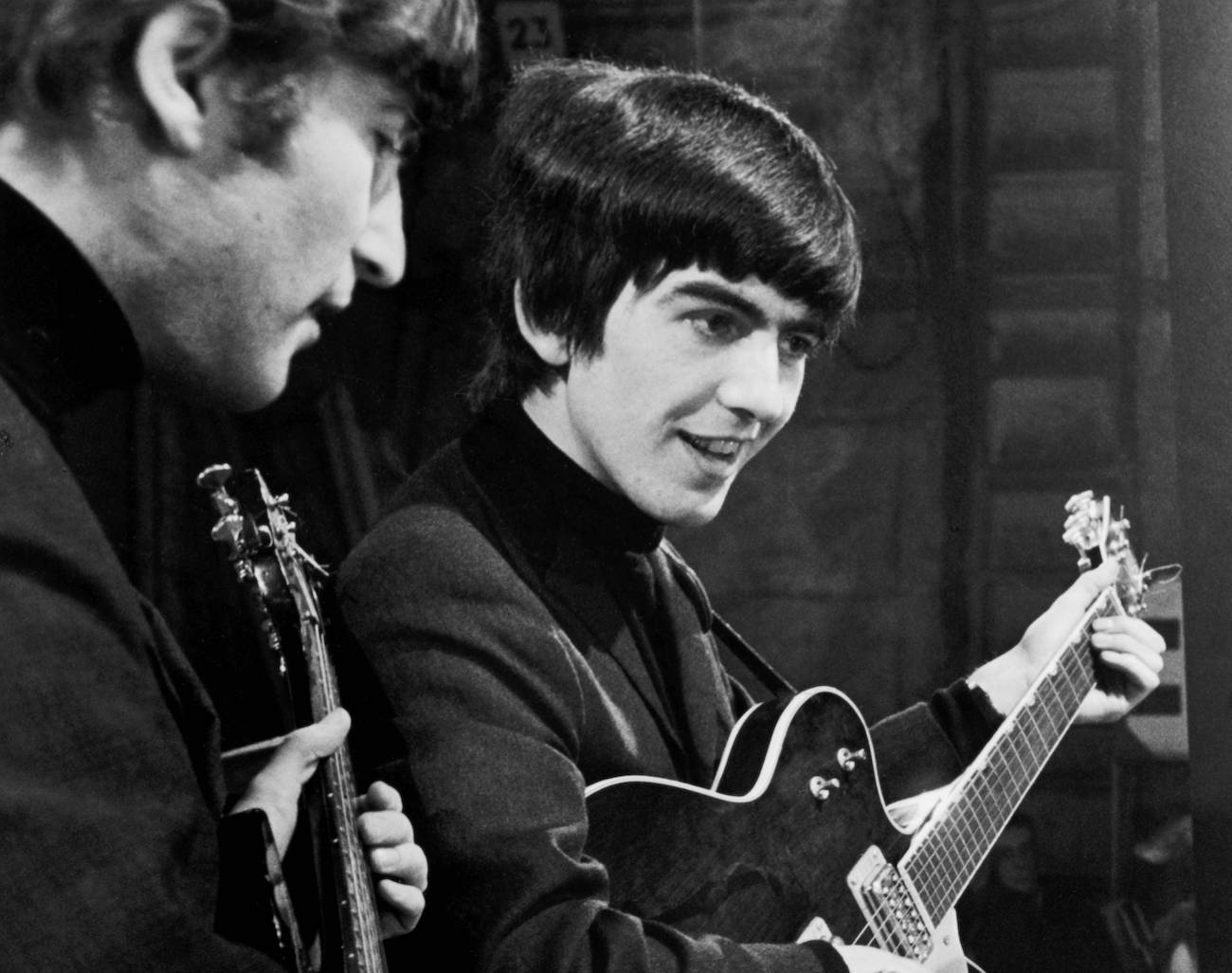 George Harrison and John Lennon wearing black on the set of a show on Alpha Television Studios in 1963.