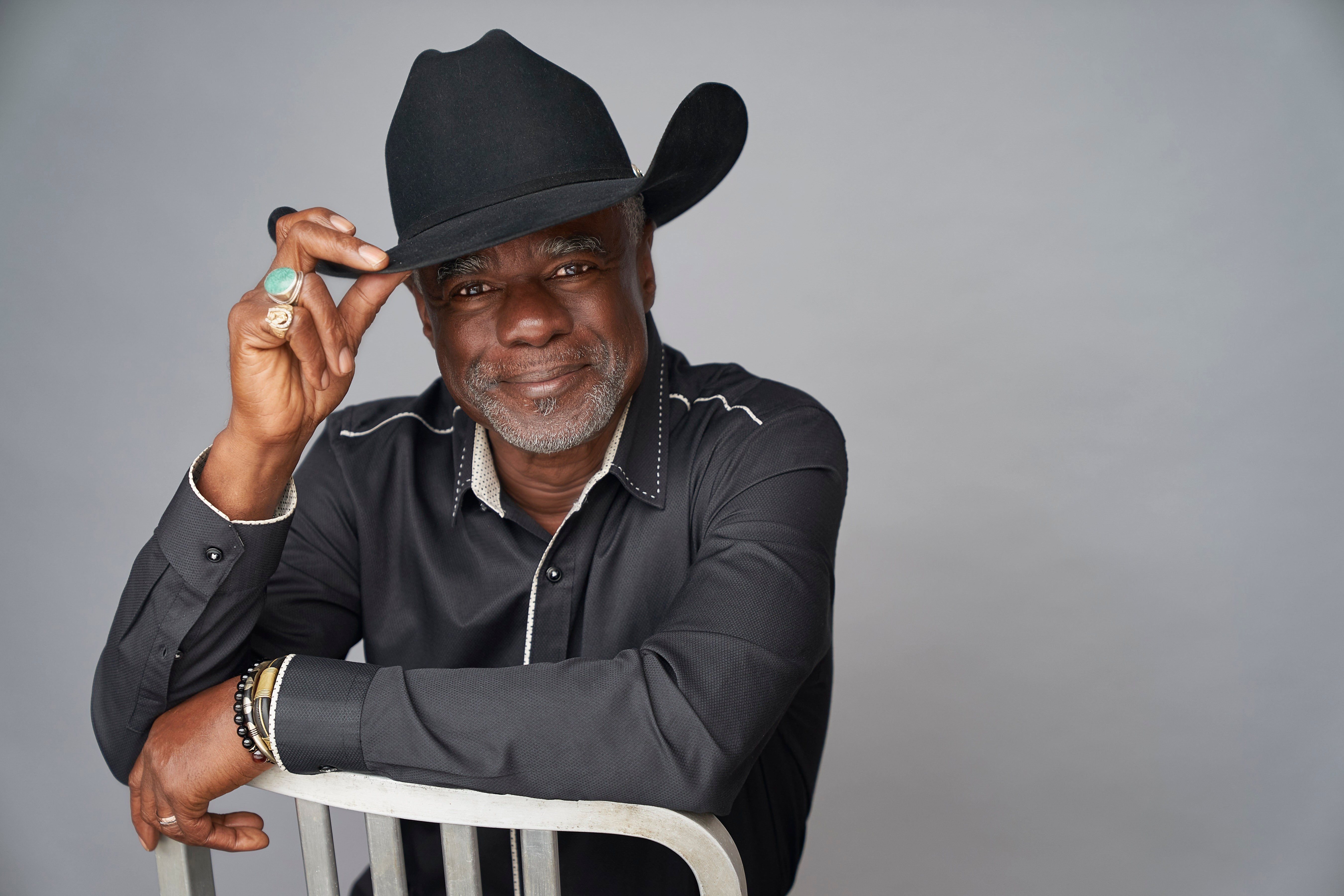 Glynn Turman posing for a photgrapher grabbing the tip of his hat