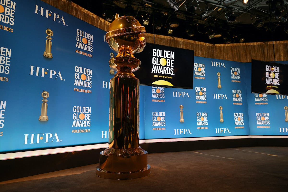 A giant statue of a Golden Globe Award sits in front of a backdrop with the awards’ logo