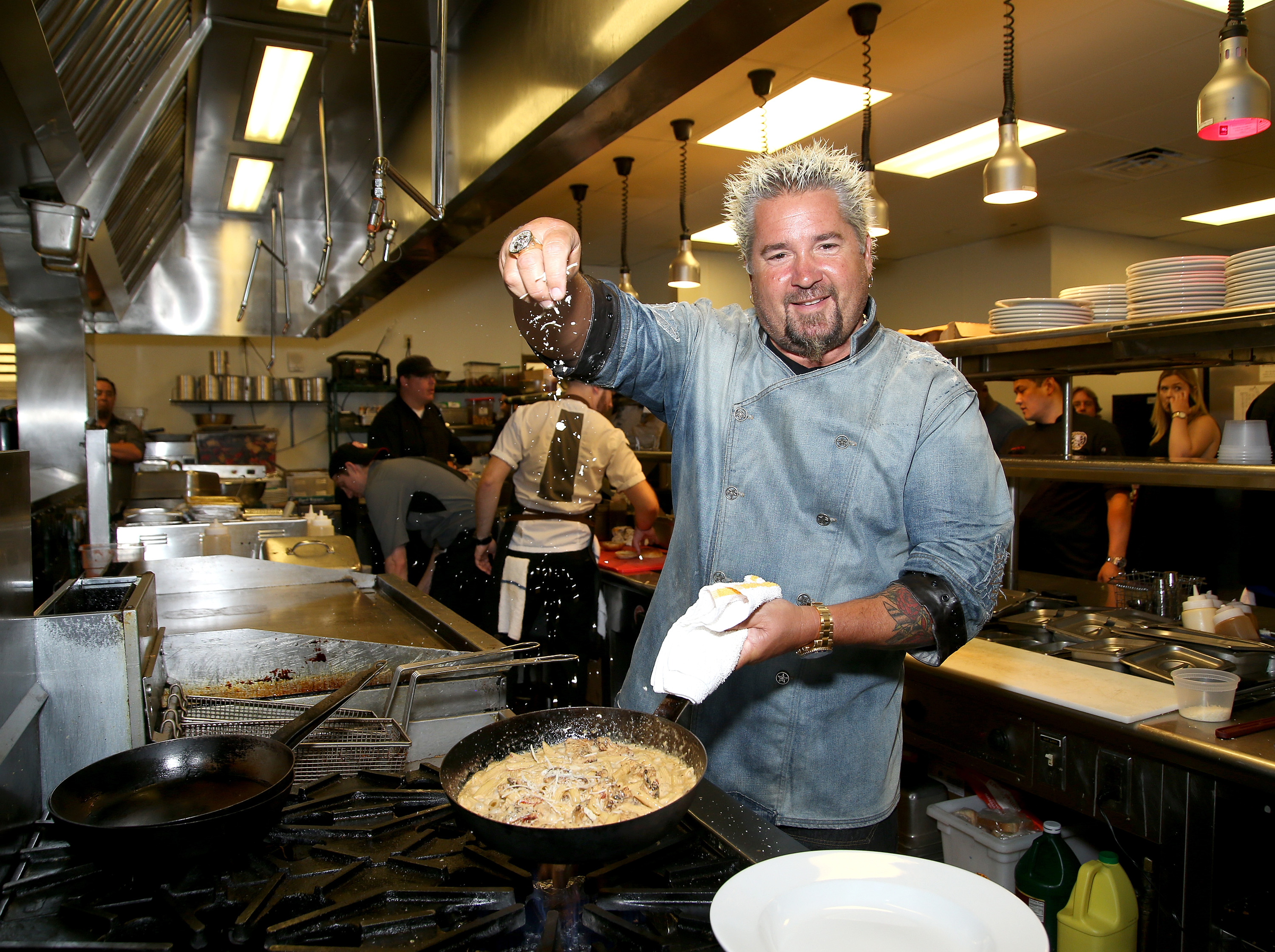 Food Network star Guy Fieri seasons a skillet meal in 2016.