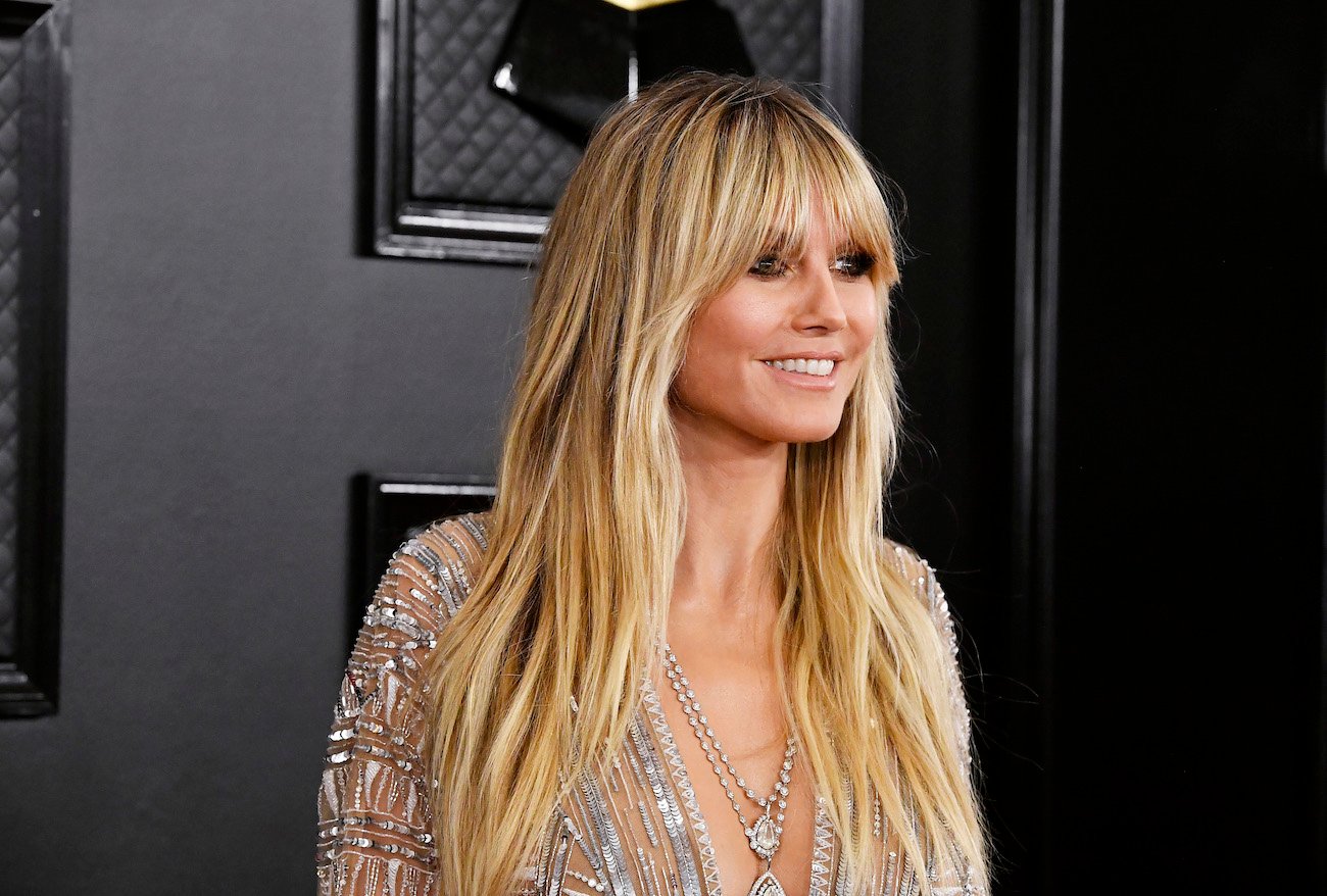 Heidi Klum standing in front of black background, looking off-camera