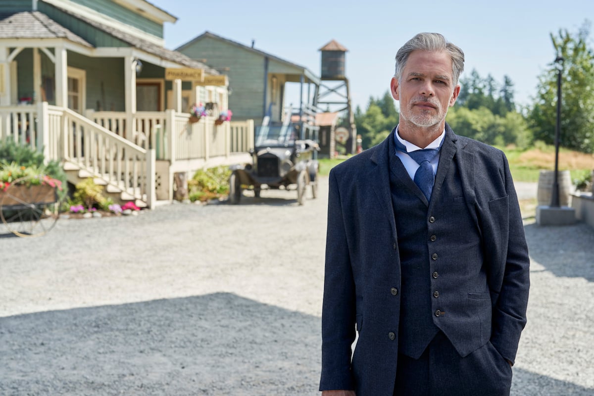 Martin Cummin as Henry Gowen, wearing a suit and standing on the street in Hope Valley in 'When Calls the Heart' Season 8