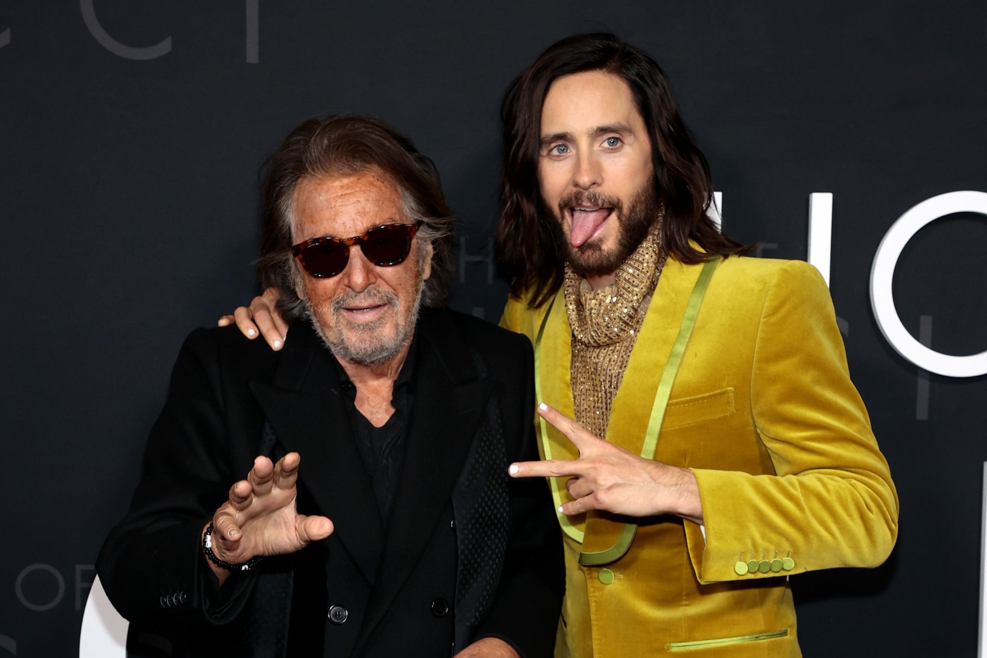 'House of Gucci' Al Pacino and Jared Leto holding up a hand in front of 'House of Gucci' logo