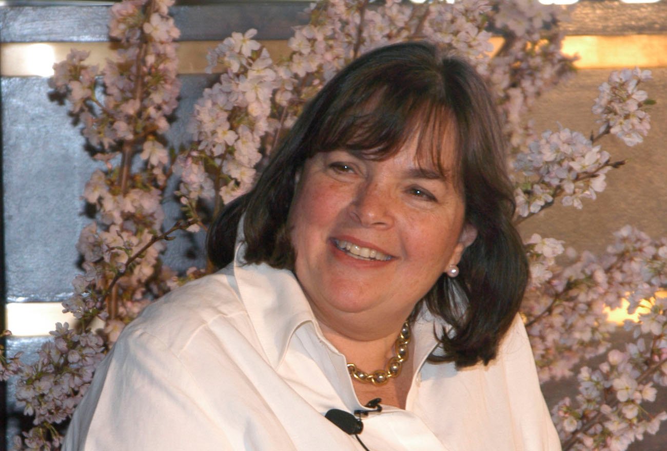 Ina Garten smiles as she looks on wearing a white shirt