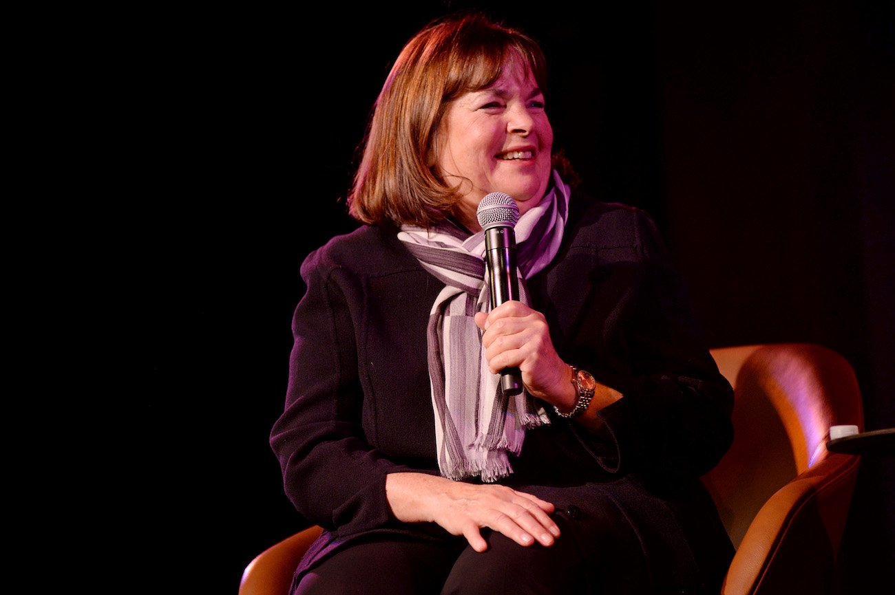 Ina Garten smiles and looks on as she holds a microphone