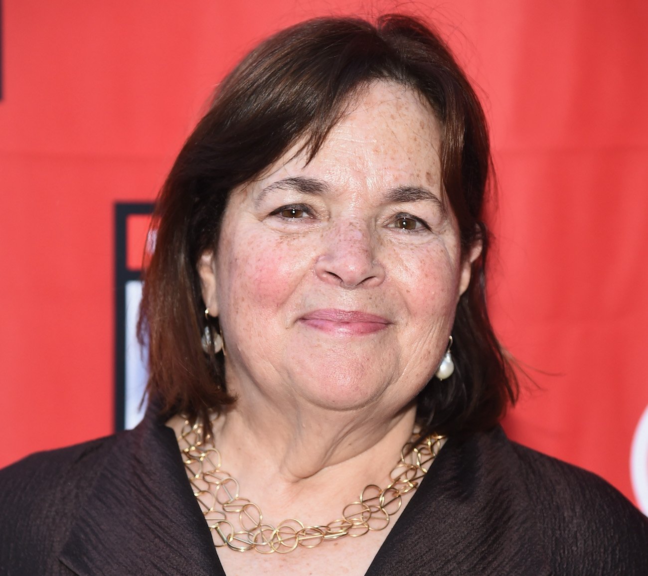 Ina Garten smiles as she poses for cameras wearing a brown blazer