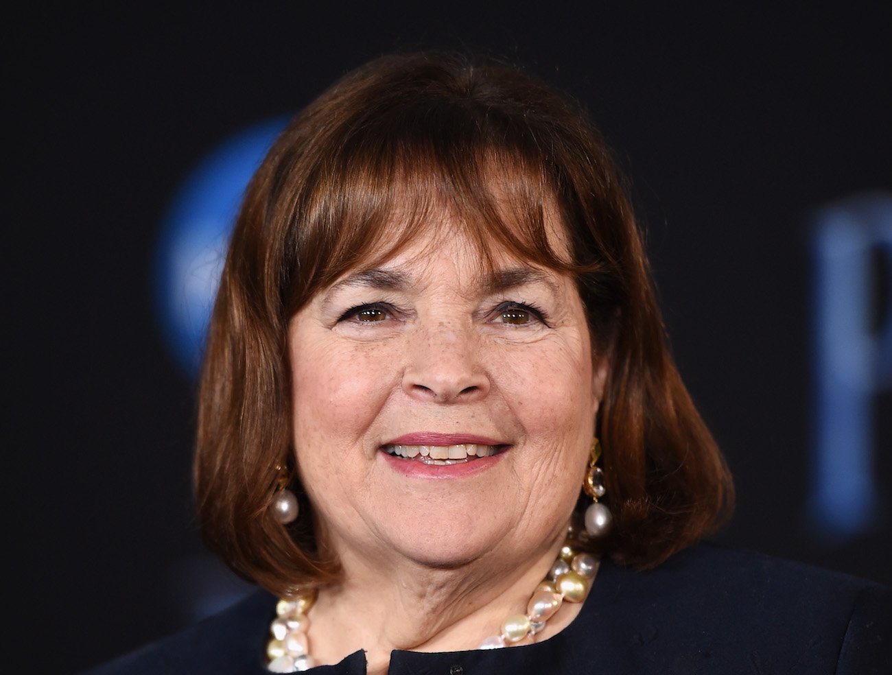 Ina Garten smiles wearing a black top and pearl necklace