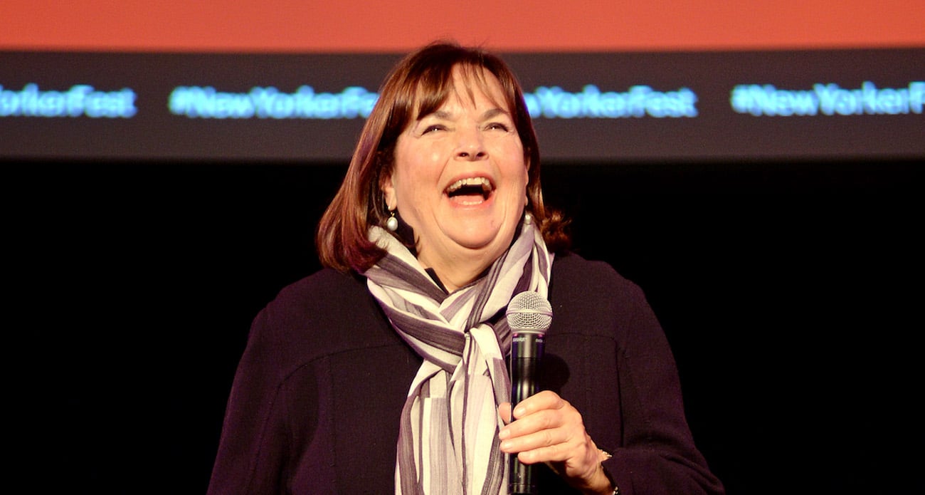 Ina Garten smiles as she holds a microphone and looks on