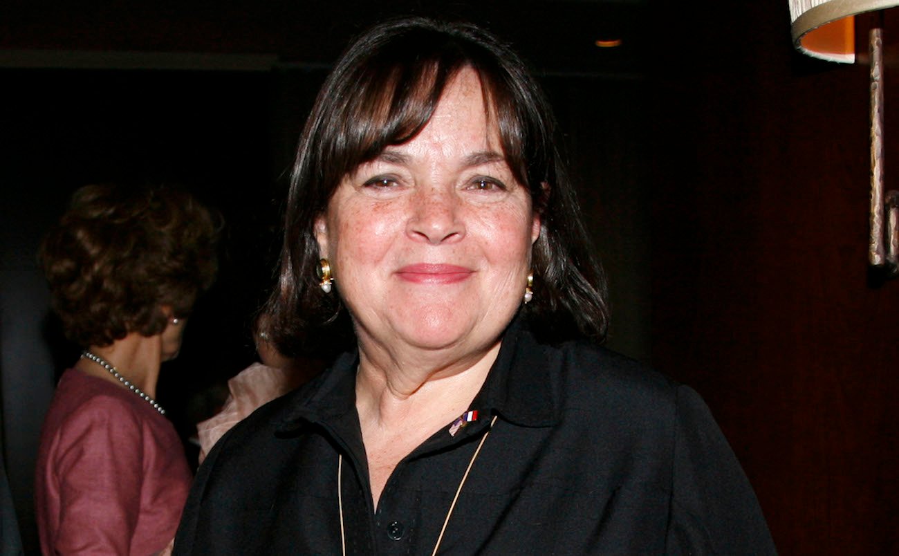 Ina Garten smiles as she poses for photographers wearing a brown button-down shirt