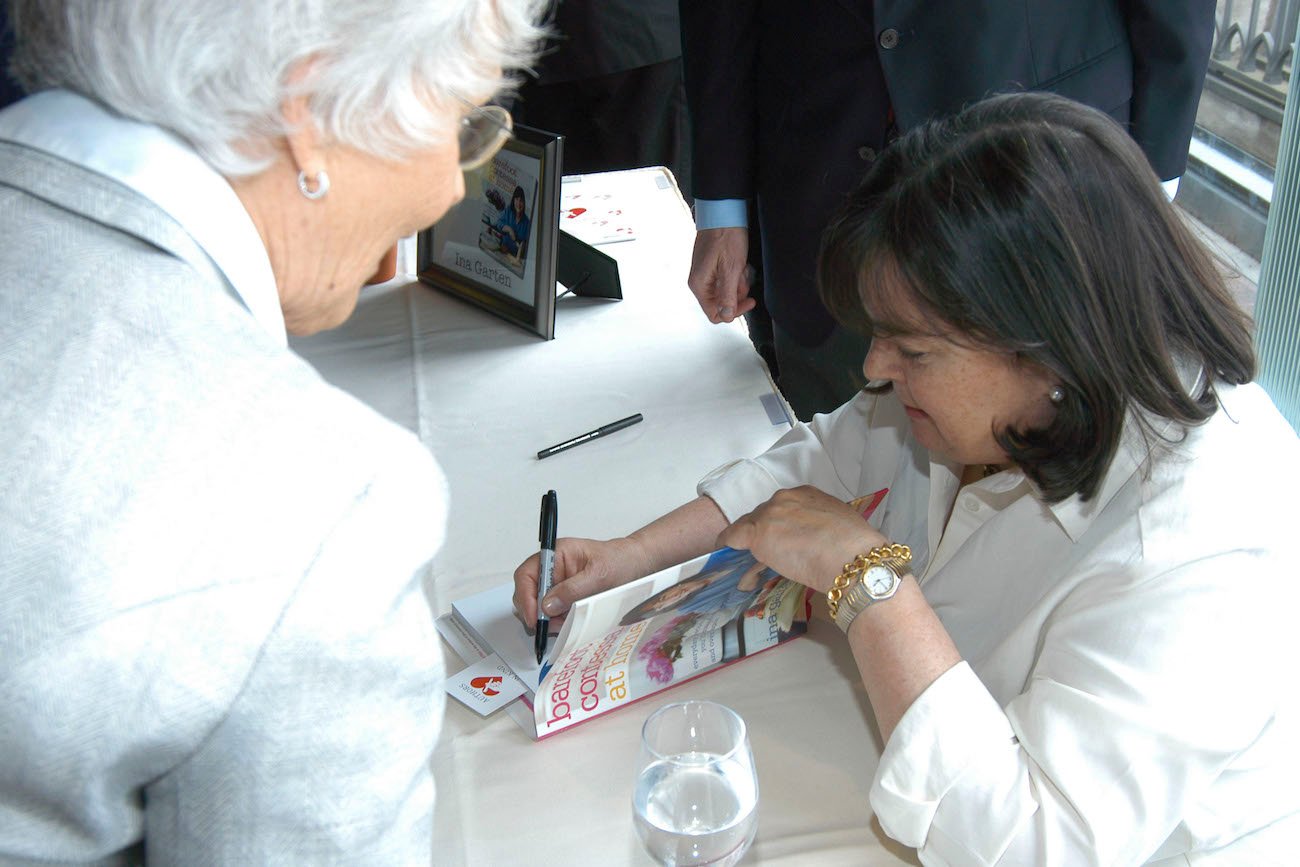 A fan watches as Ina Garten signs a copy of her cookbook