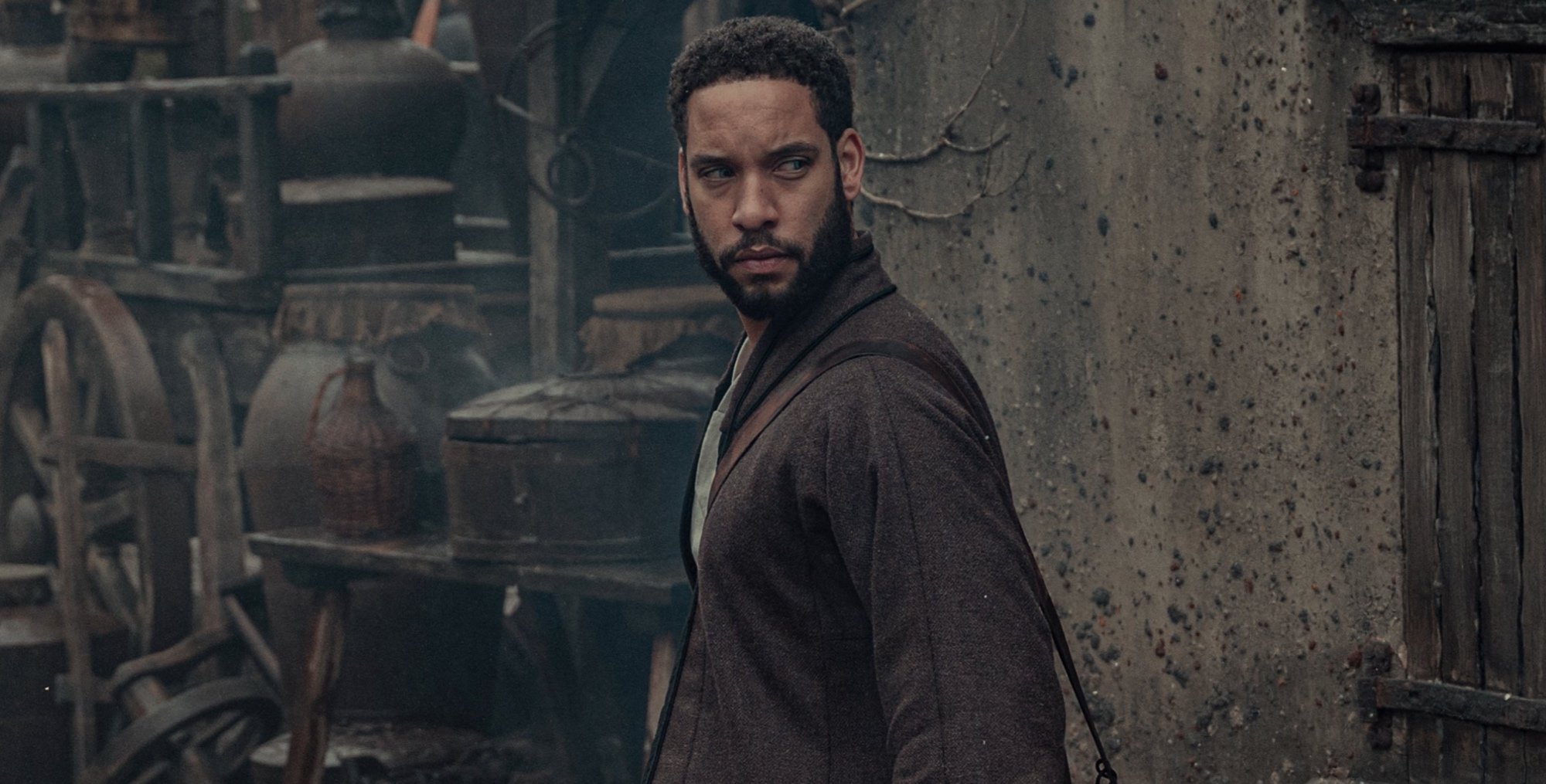 Istredd in 'The Witcher' Season 2 wearing brown cloak and walking in town.