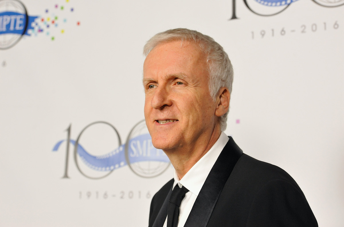 James Cameron smiling in front of a white background