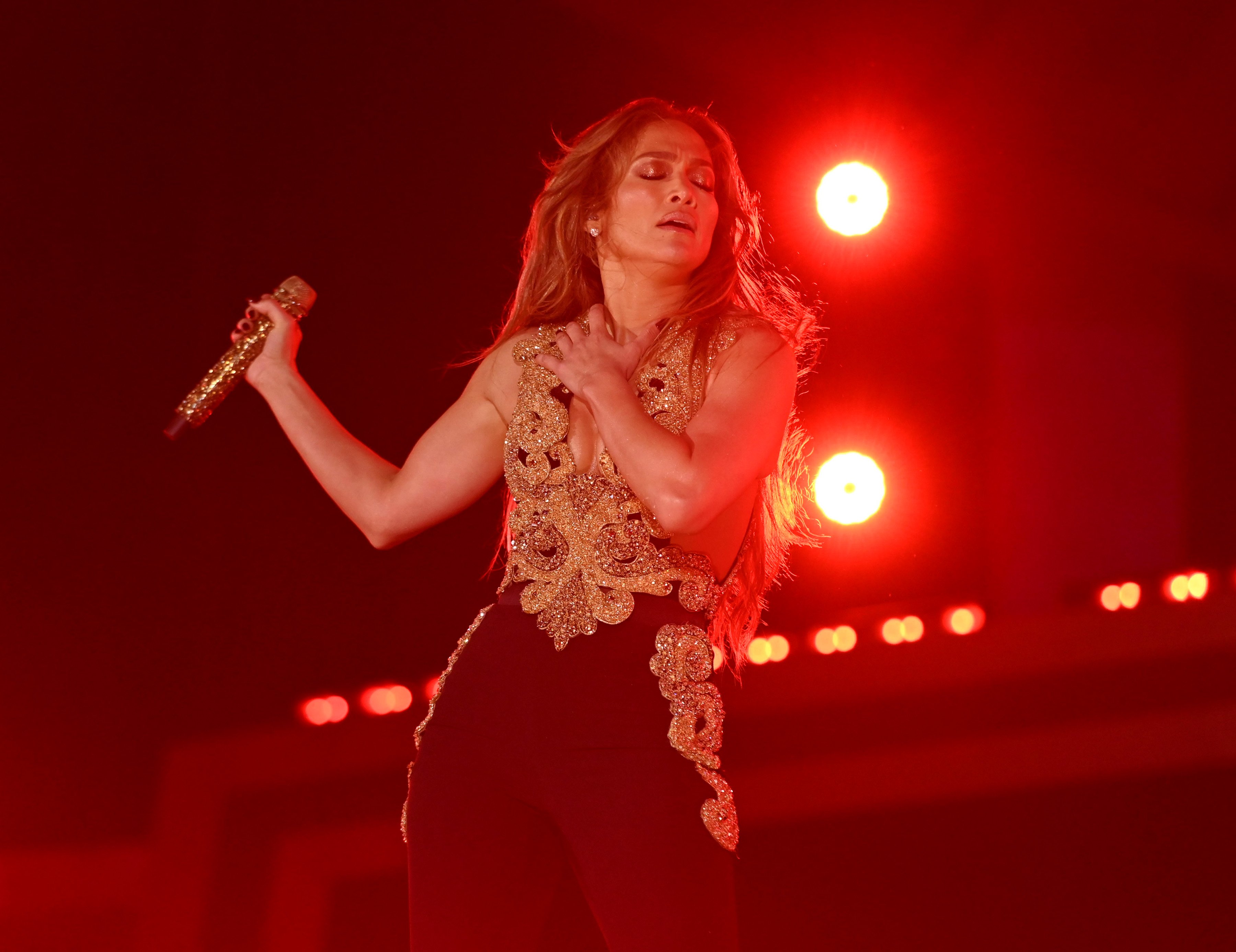 Jennifer Lopez closes her eyes and holds a microphone