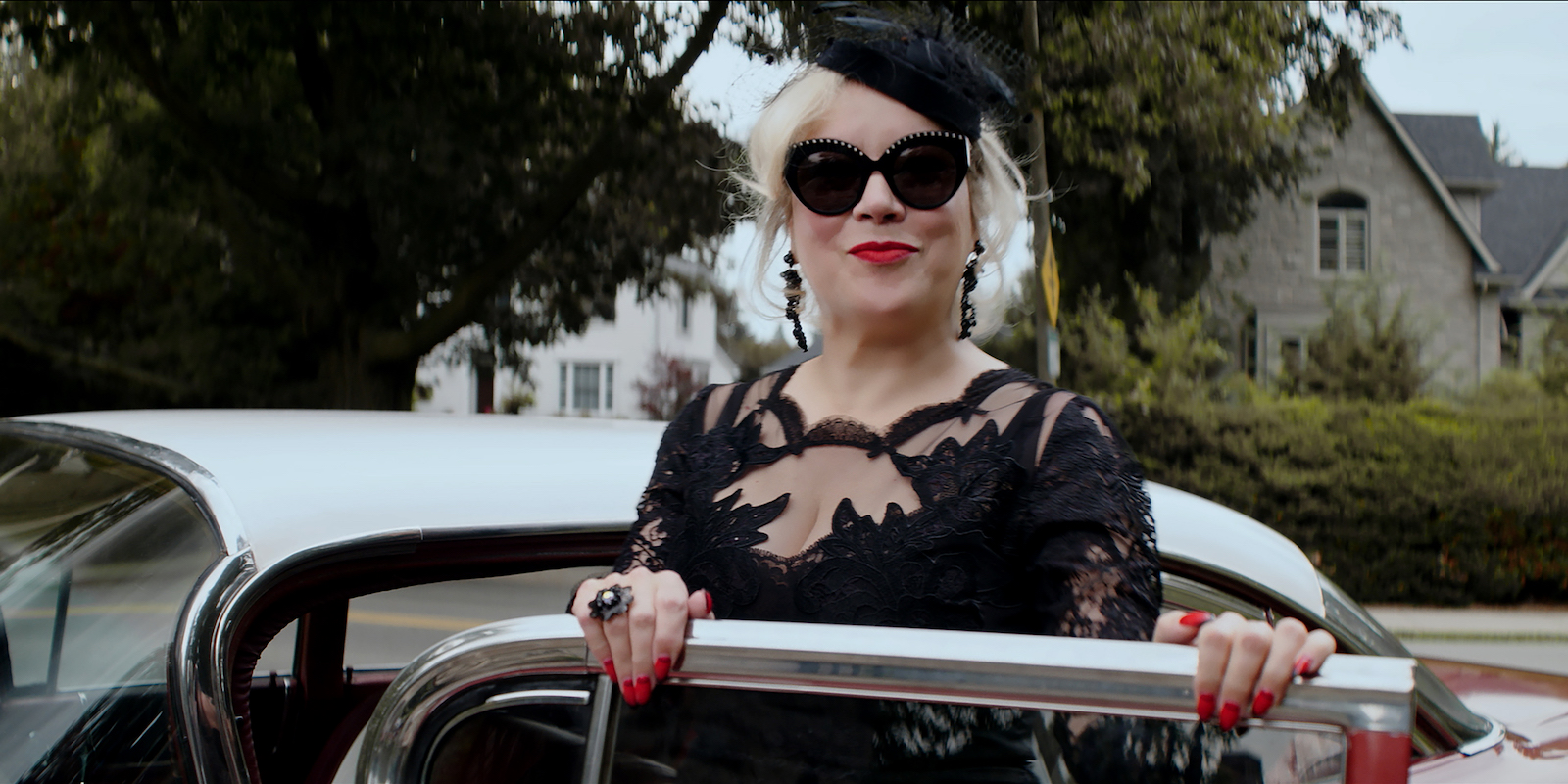 Jennifer Tilly exits a white car wearing a black dress and sunglasses