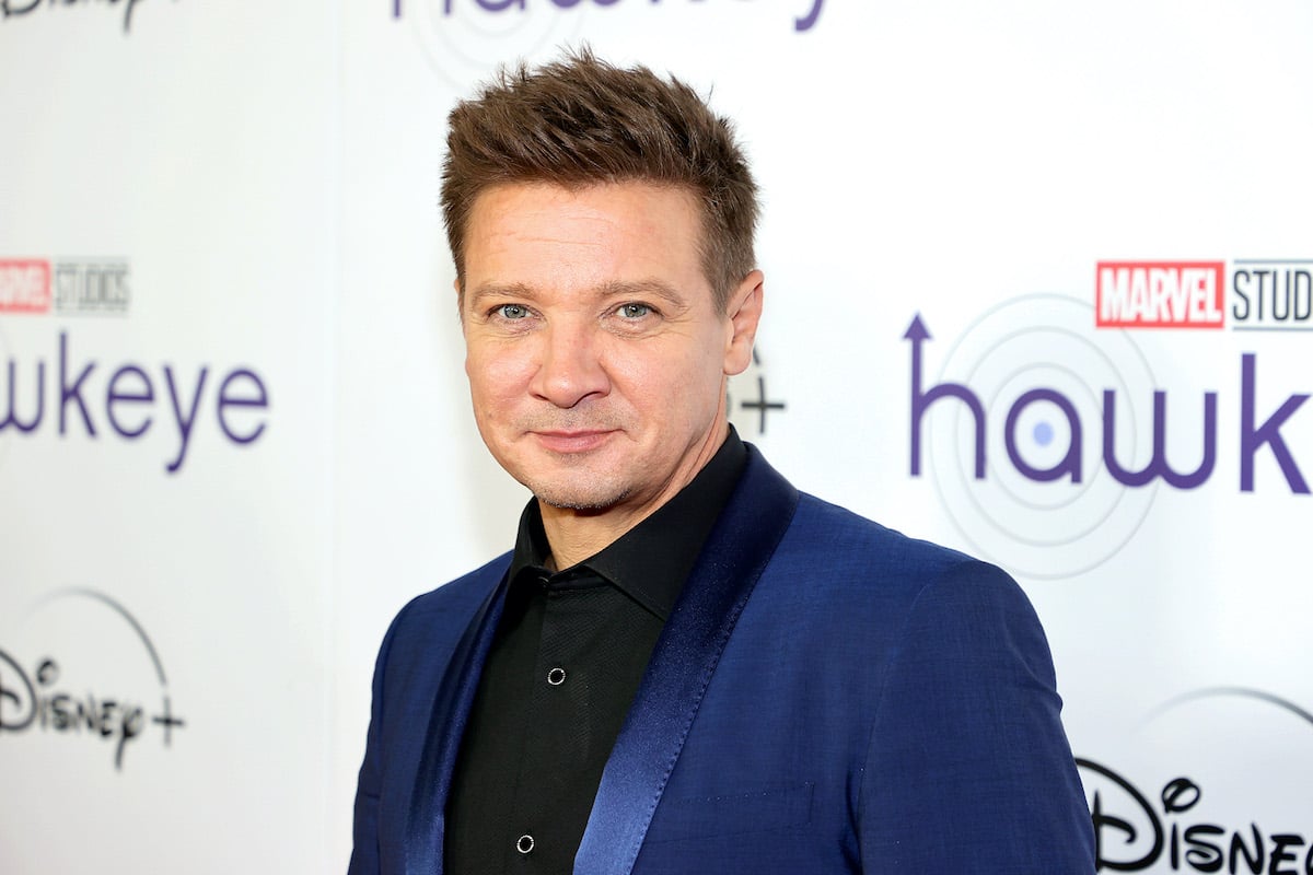 Jeremy Renner smiling in front of a white background