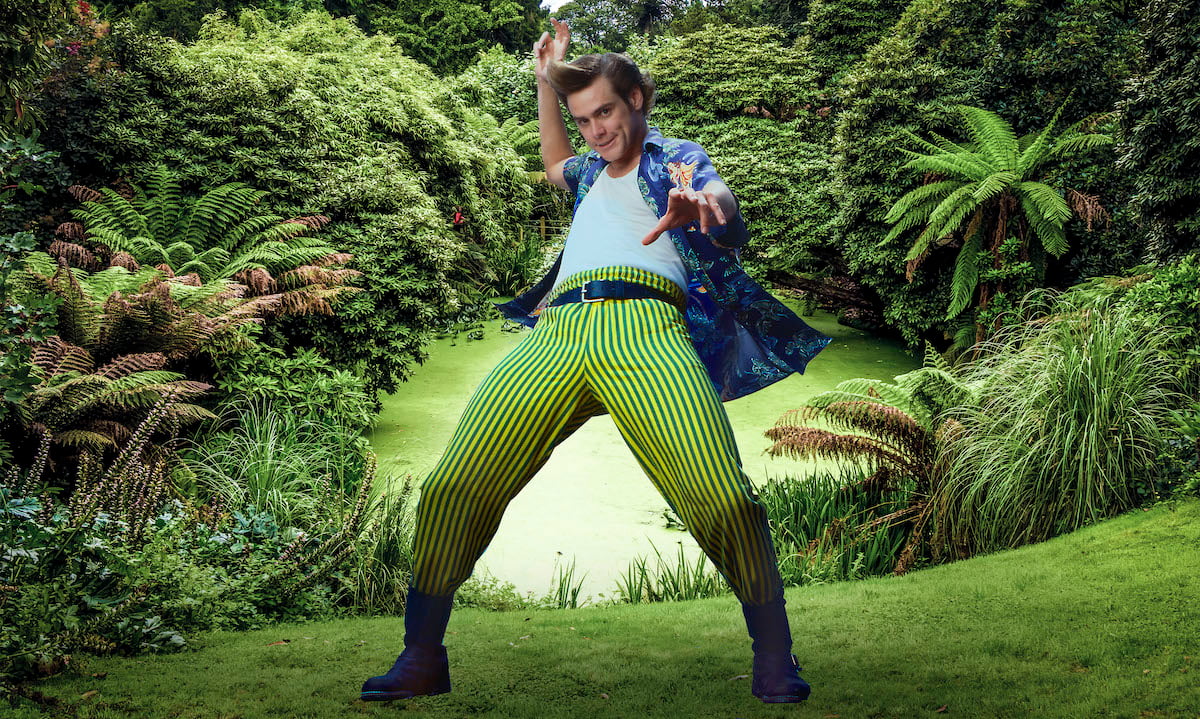 Jim Carrey as Ace Ventura points to the camera amid a jungle background