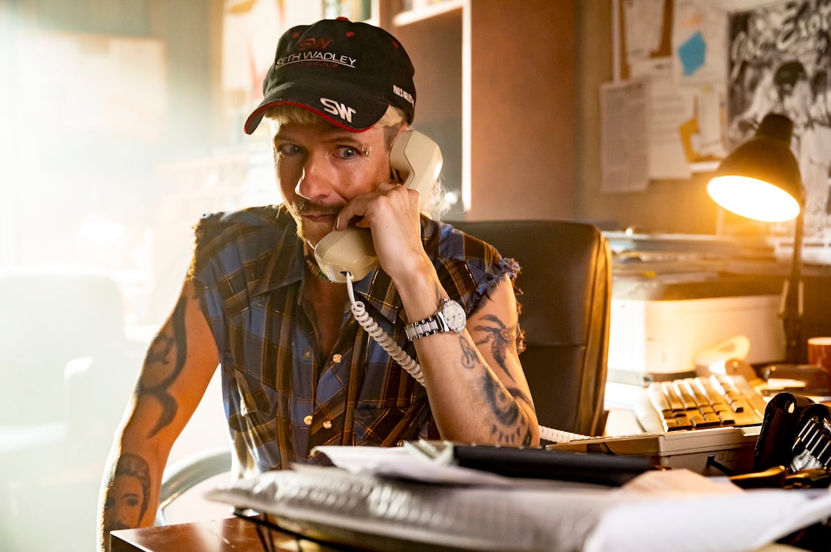 John Cameron Mitchell as Joe Exotic, wearing a baseball cap and talking on the phone, in 'Joe vs. Carole'