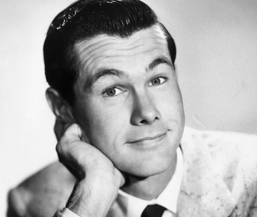 Johnny Carson rests his chin on his hand in a promotional headshot portrait