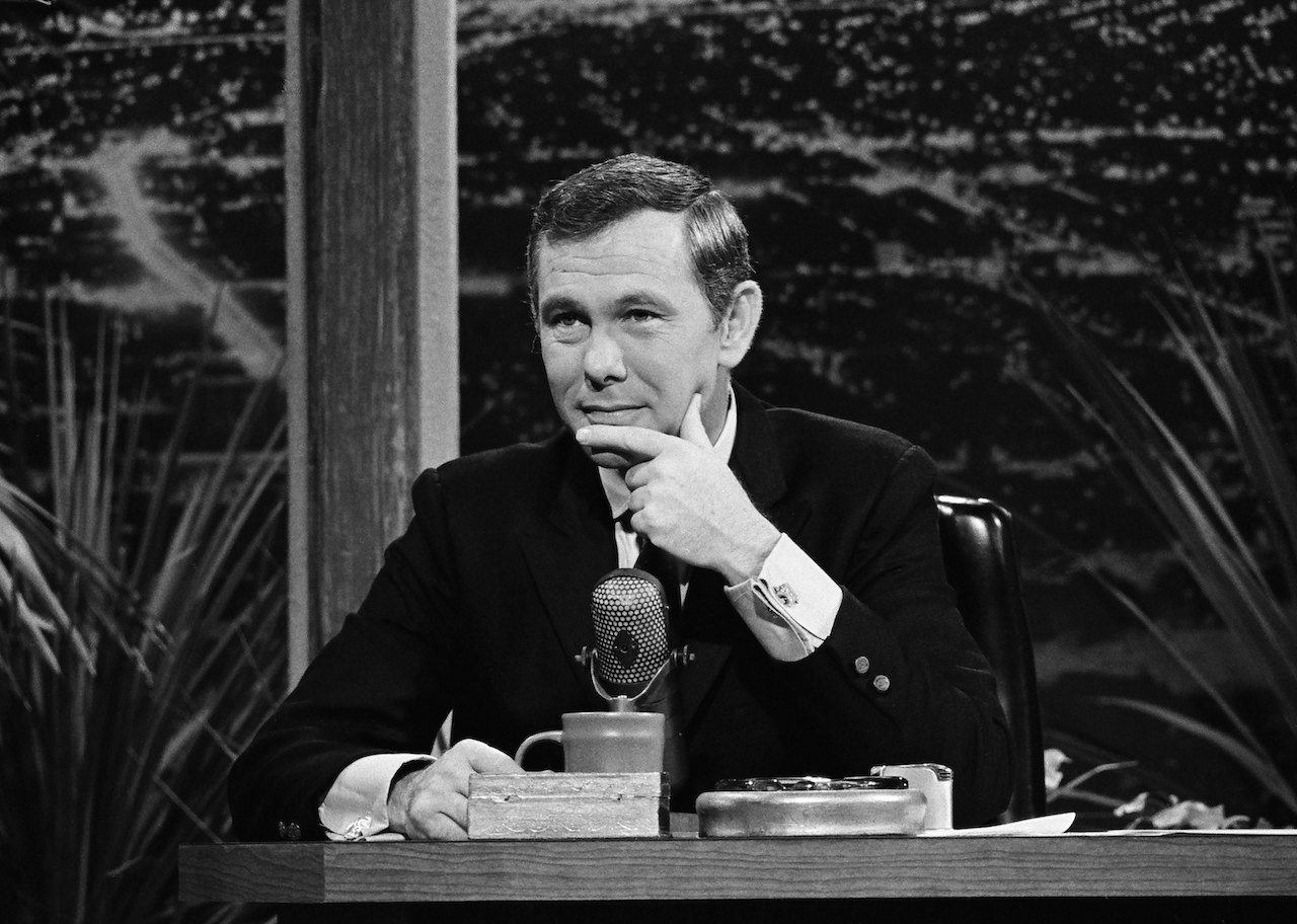 Black and white photo of Johnny Carson from 1967, sitting at 'The Tonight Show' desk with his chin