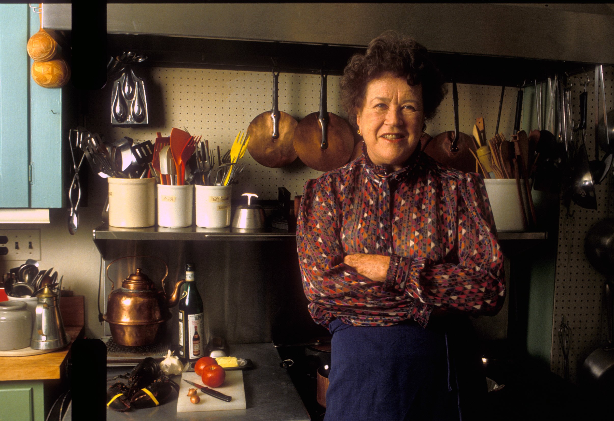 Julia Child smiles with her arms crossed