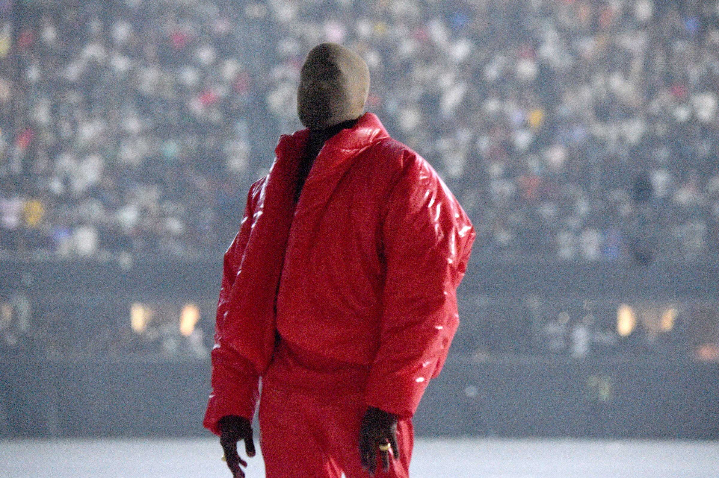 Kanye West wearing red and a face covering