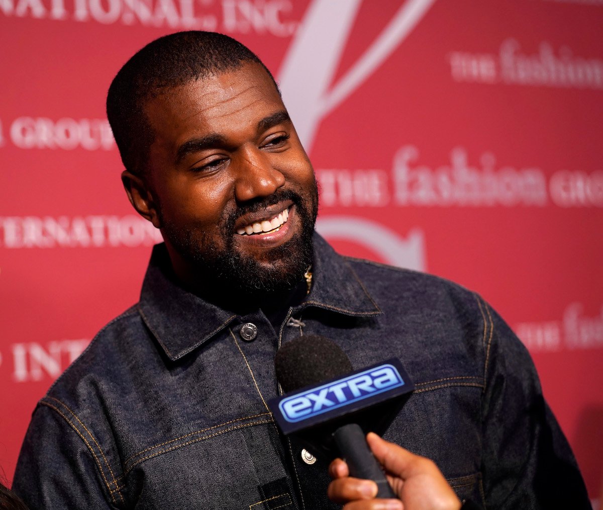 Kanye West smiles into a microphone.