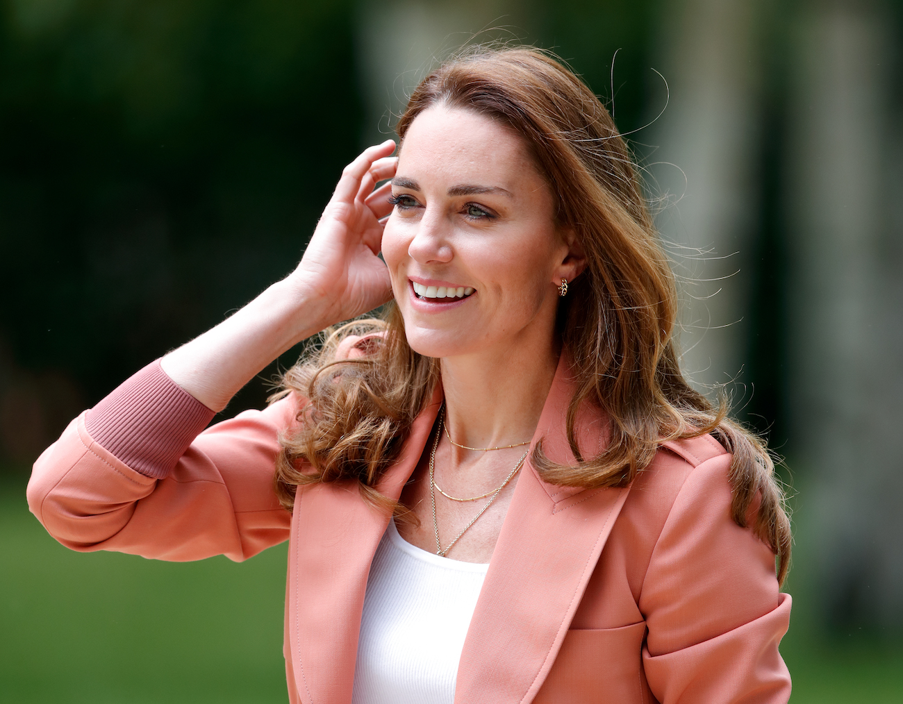 Kate Middleton smiling while wearing a salmon-colored jacket