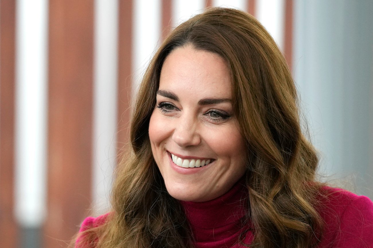 Kate Middleton smiles wearing a red top