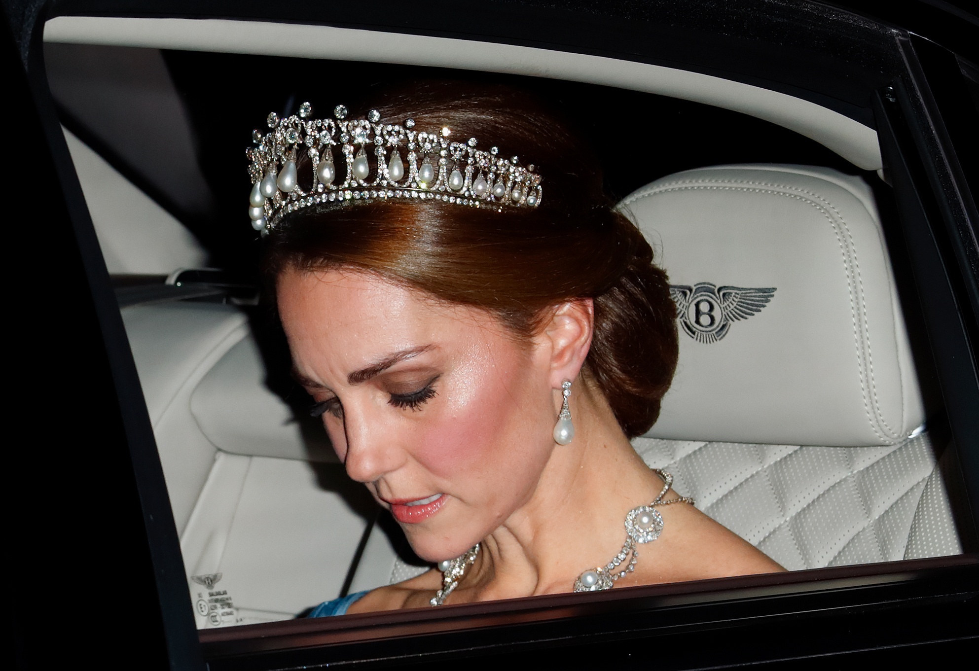 Kate Middleton in a car wearing a tiara with her head bent down 