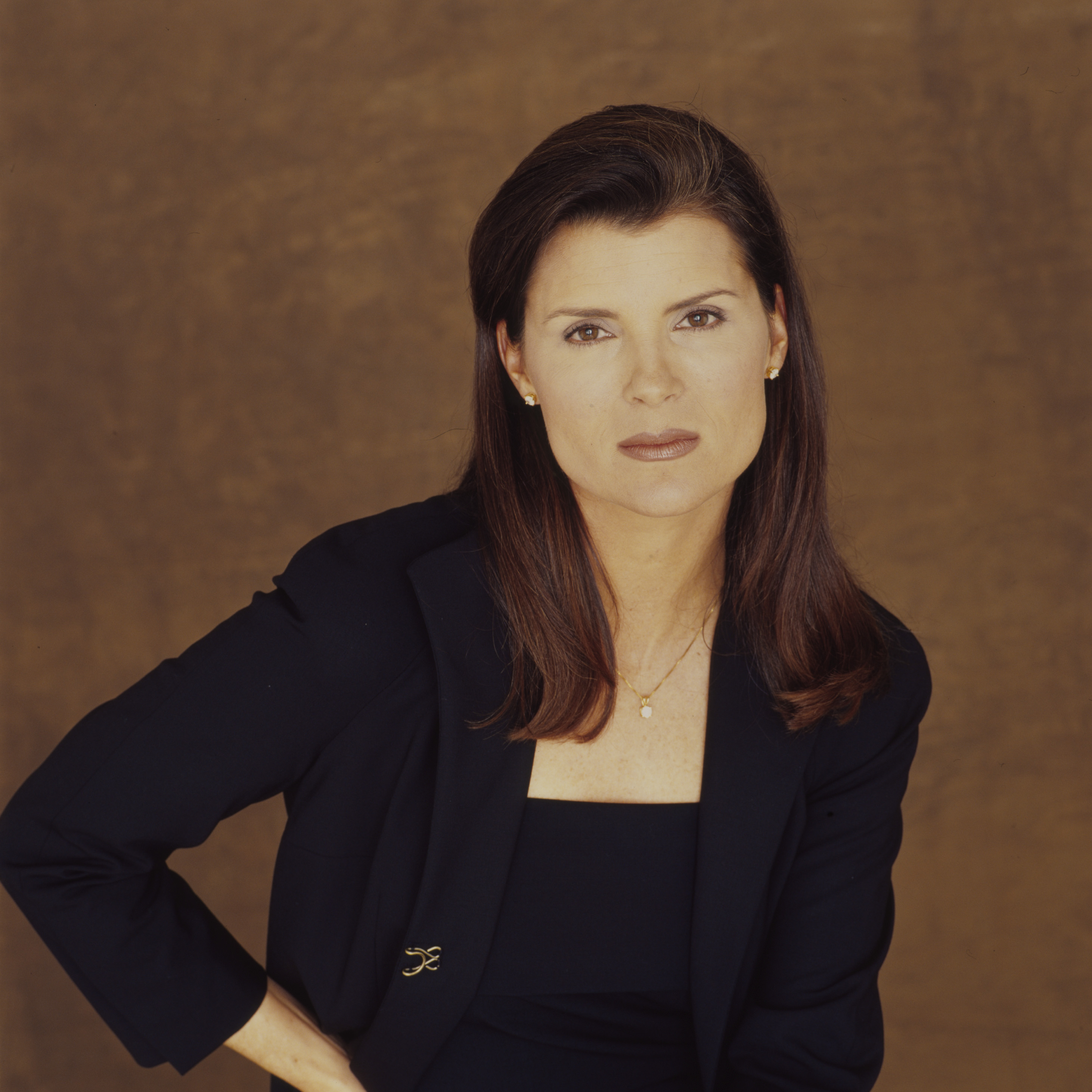 'The Bold and the Beautiful' actor Kimberlin Brown wearing a blue suit and posing in front of a brown backdrop.