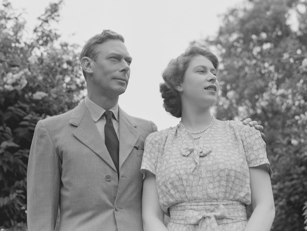 King George VI and then-Princess Elizabeth standing in the gardens of Windsor Castle (circa 1946)