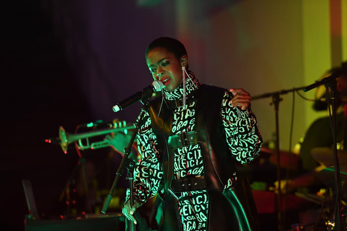 Lauryn Hill wearing a black and white jacket while performing on stage.