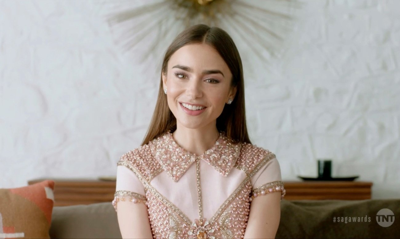 Lily Collins wearing a bejeweled top, smiling