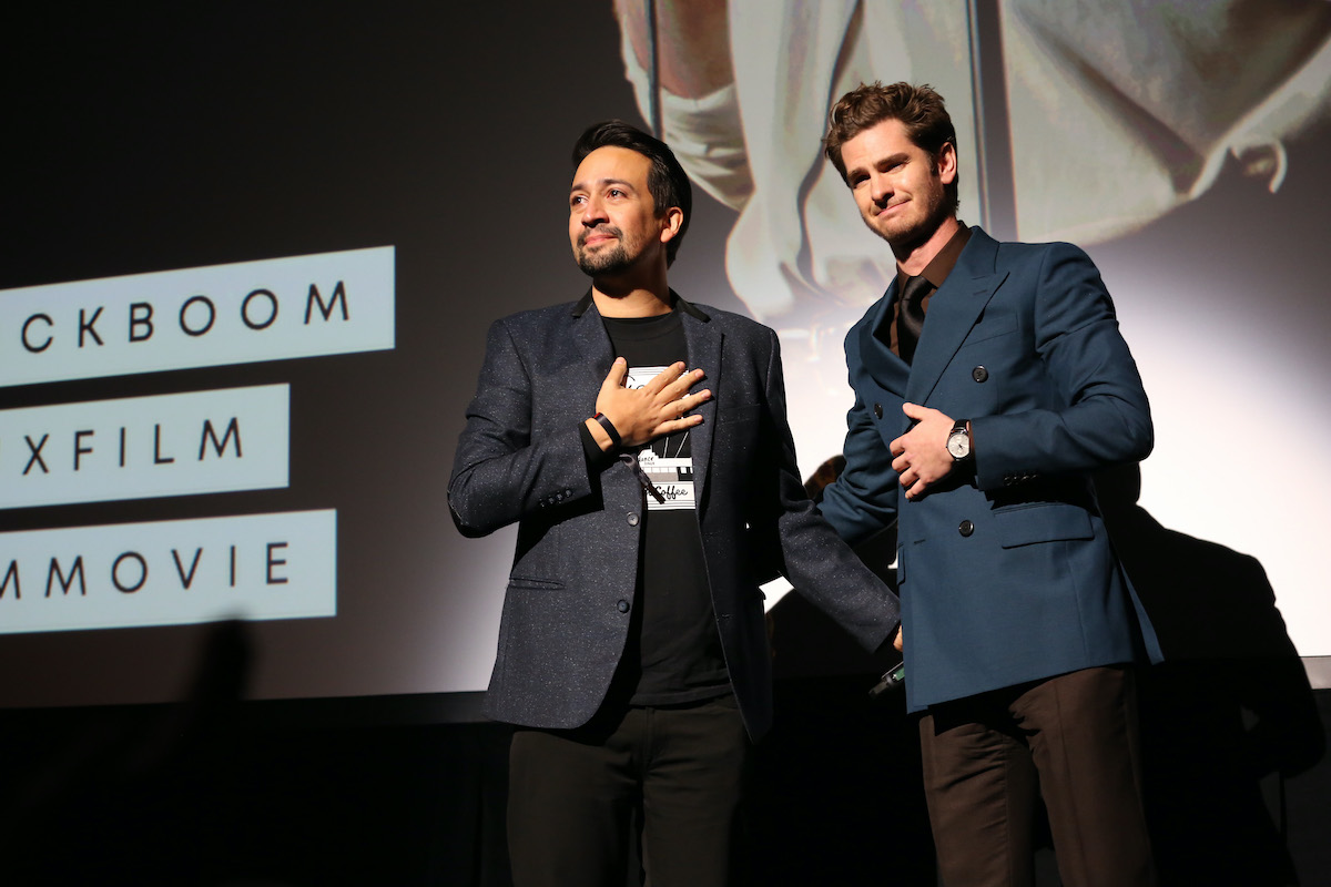 Lin-Manuel Miranda and Andrew Garfield wear suits while onstage