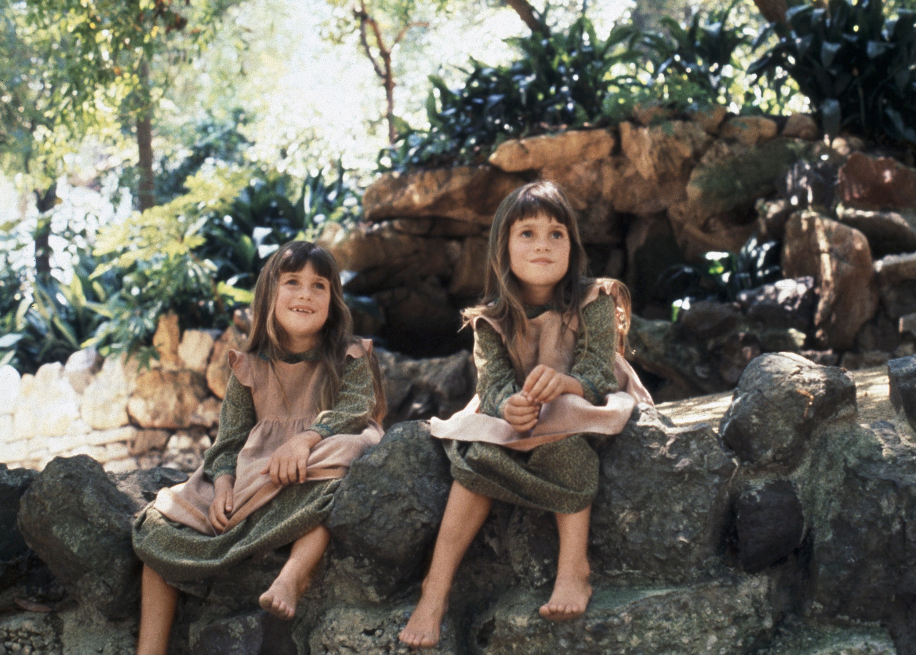 Lindsay and Sidney Greenbush as Carrie Ingalls, sitting on a rock while wearing their prairie clothes