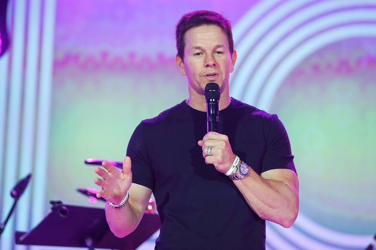 Mark Wahlberg wearing a black t-shirt while speaking into a microphone.