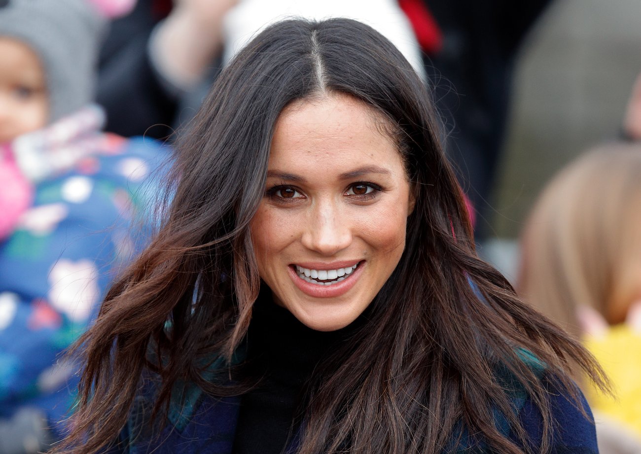 Meghan Markle looking on in a crow of people