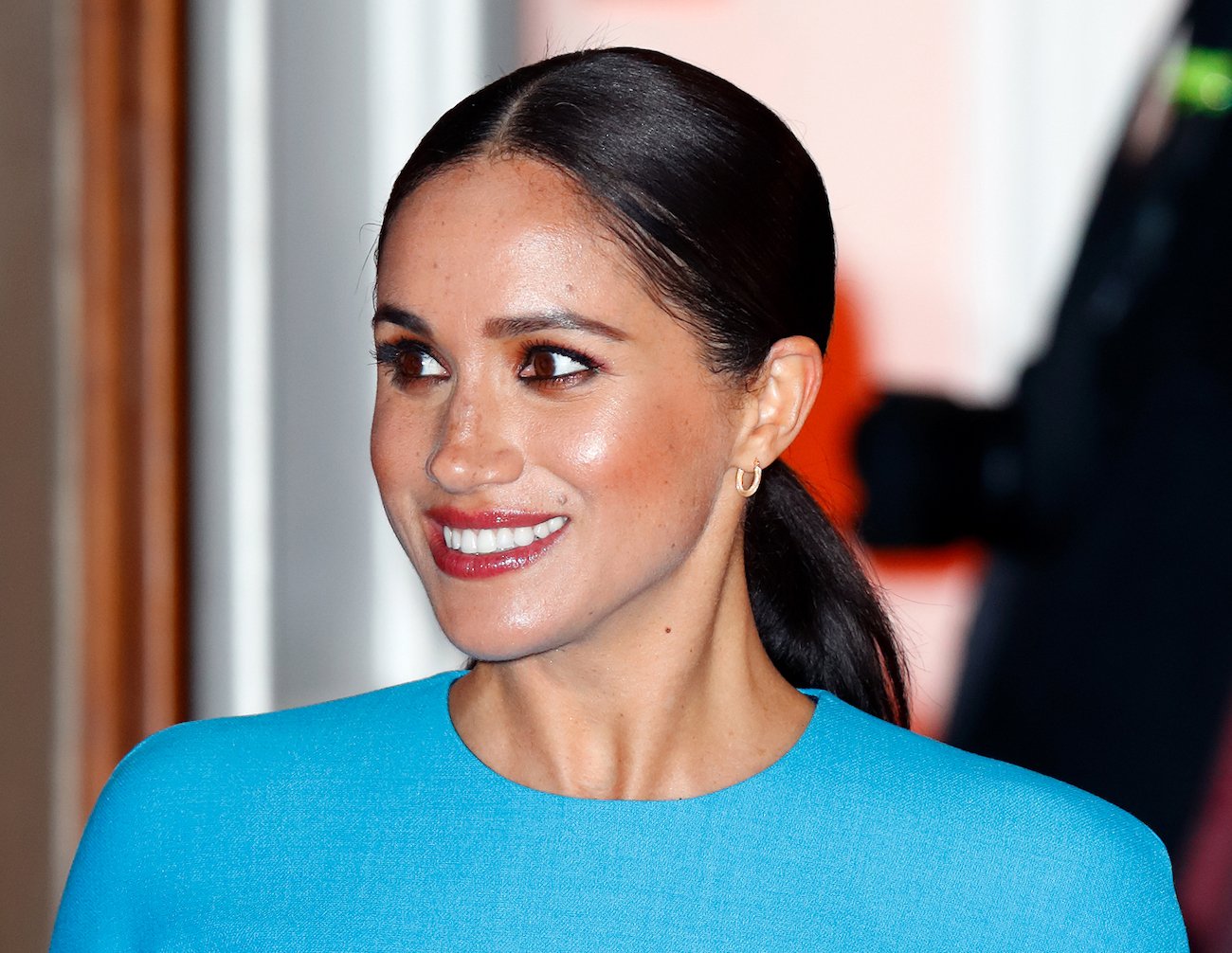 Meghan Markle wearing dark red lipstick and a blue outfit