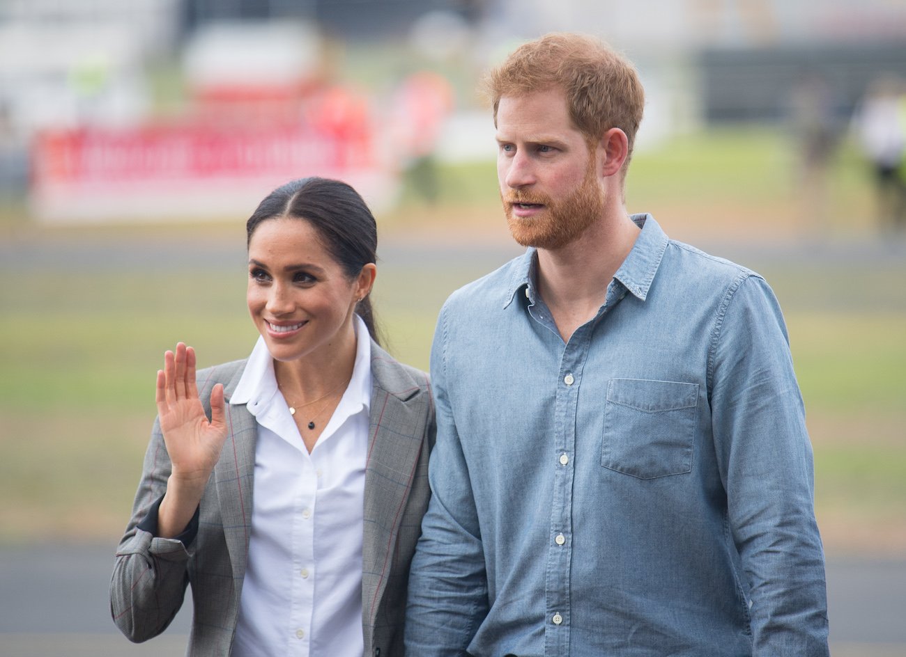 Meghan Markle waving while walking next to Prince Harry