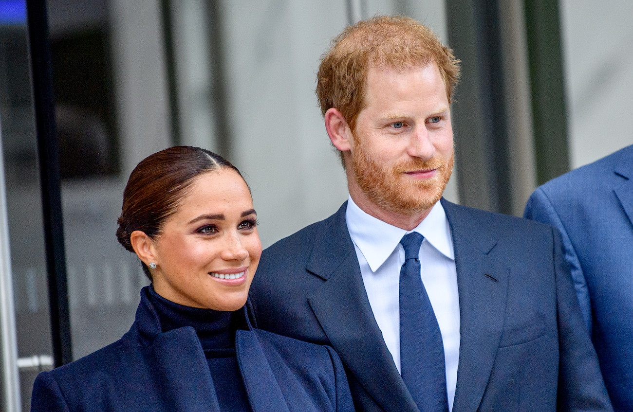 Meghan Markle and Prince Harry smiling, looking off-camera