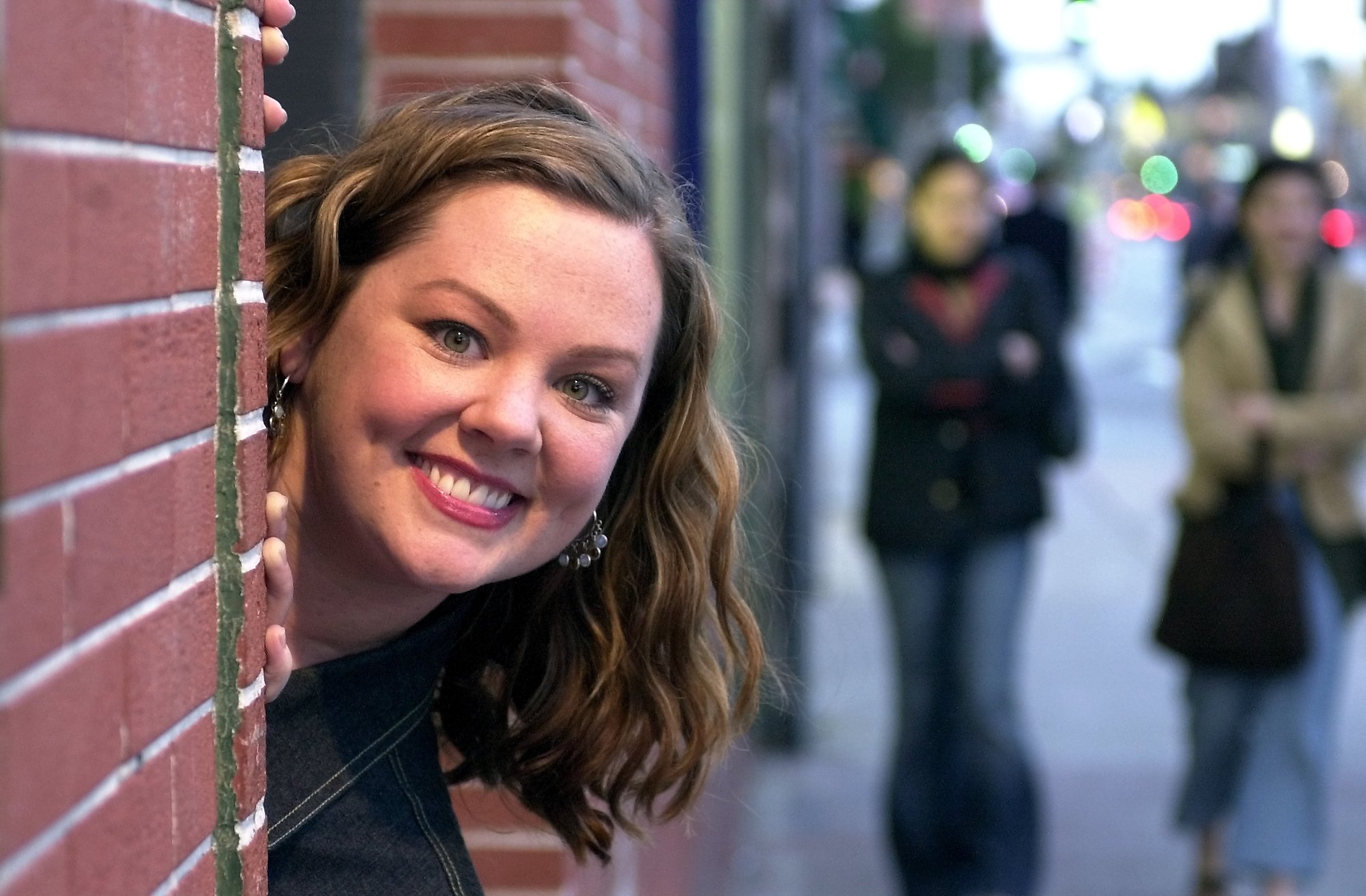 Sookie St. James actor Melissa McCarthy in promotional material for the Groundlings peeking out from behind a brick wall